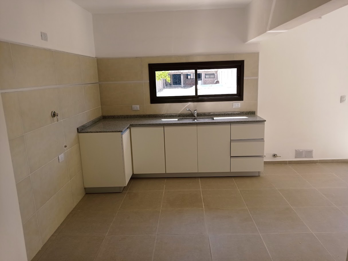 Cocina en L con mesada de granito y muebles claros